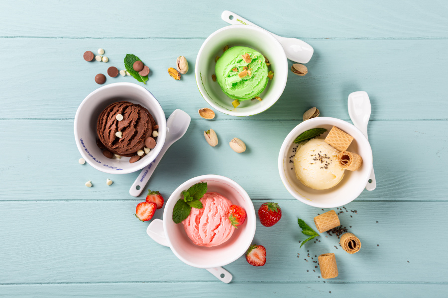 Vier Schälchen Eis in verschiedenen Sorten mit Früchten und Toppings